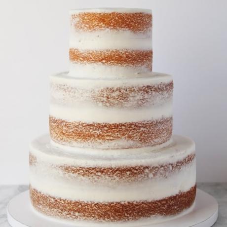 Undecorated three tier semi naked wedding cake.